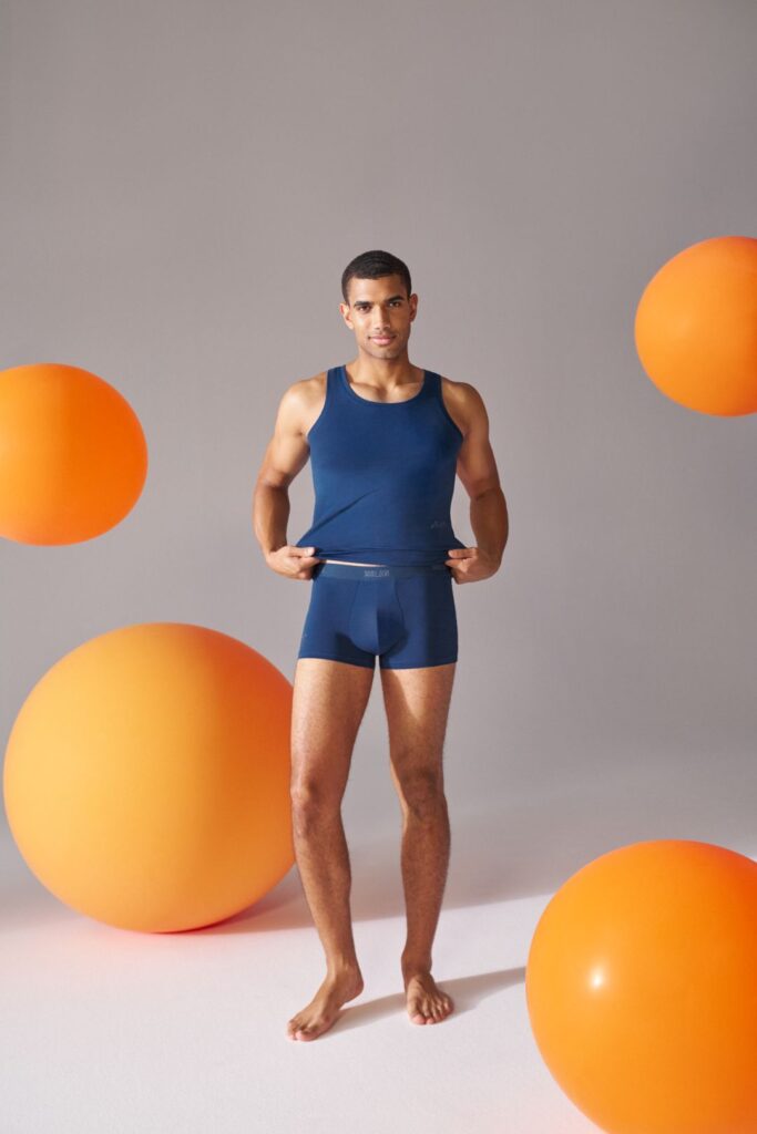 Homem em roupa interior azul com bolas laranja.