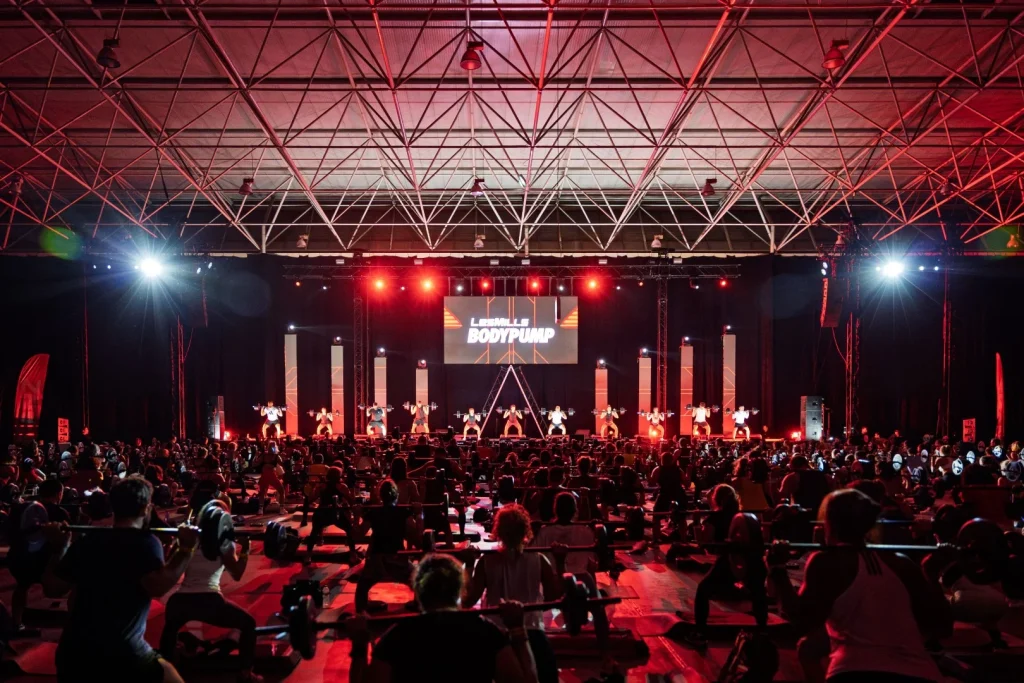 Grande evento Bodypump Les Mills com multidão a exercitar-se.