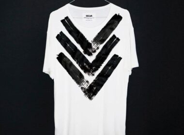Camiseta branca com padrão de setas pretas.