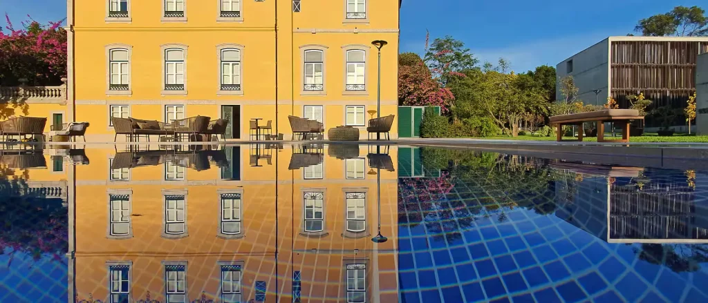 Edifício amarelo refletido em piscina clara.