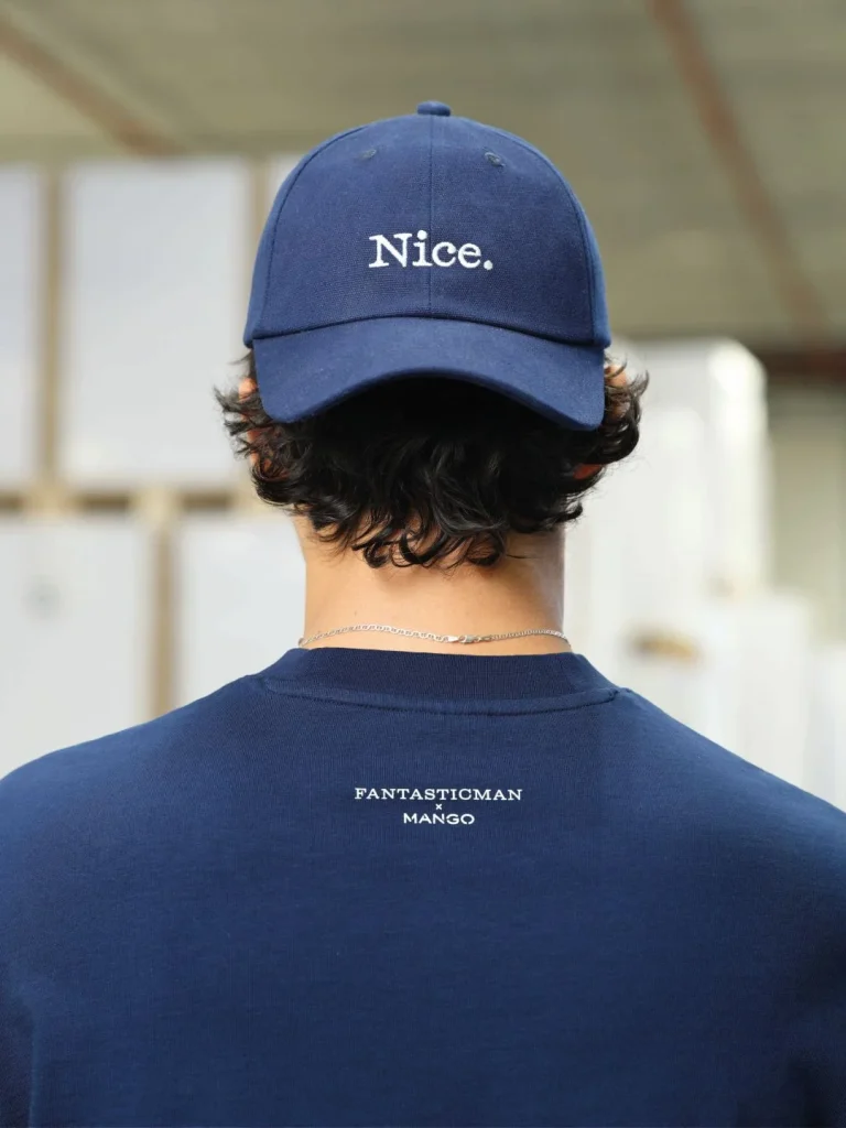 Homem de costas com boné azul "Nice." e camisola FANTASTICMAN x MANGO.