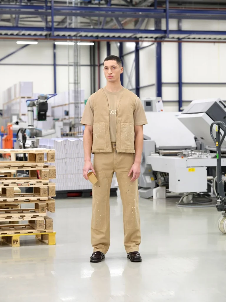 Homem de roupa de trabalho bege em armazém industrial.