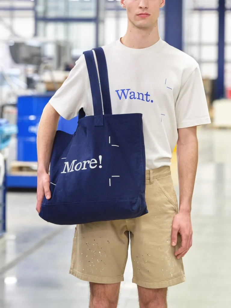 Homem com t-shirt "Want." e saco tote "More!".