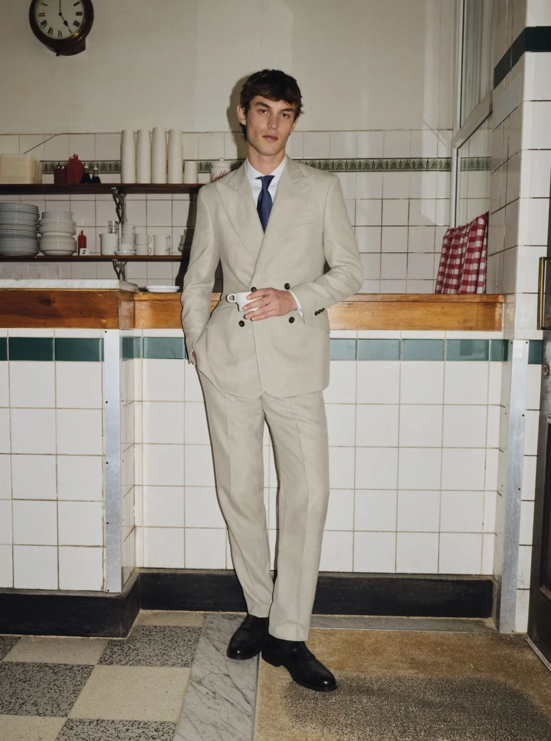 Homem de fato bege numa cozinha vintage.