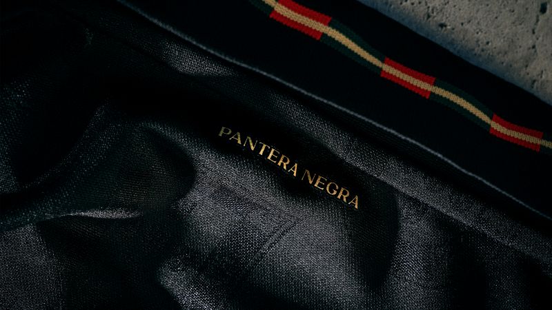 Tecido preto com texto 'Pantera Negra' bordado.