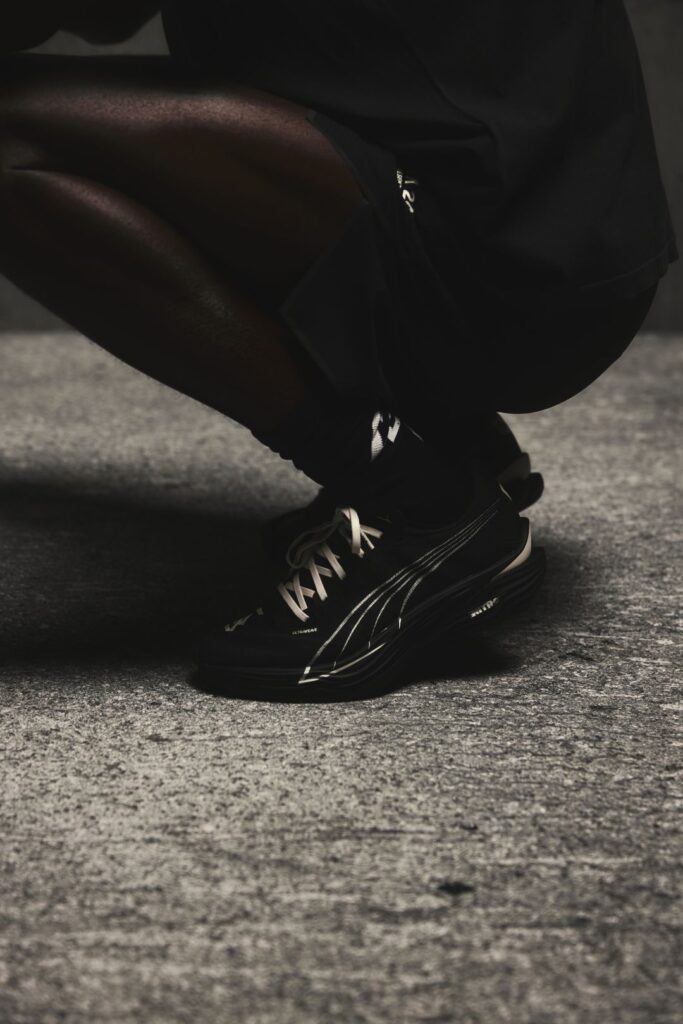 Pessoa agachada com sapatos desportivos pretos.