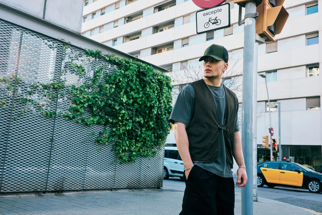 Homem com look urbano posando junto a parede com hera.