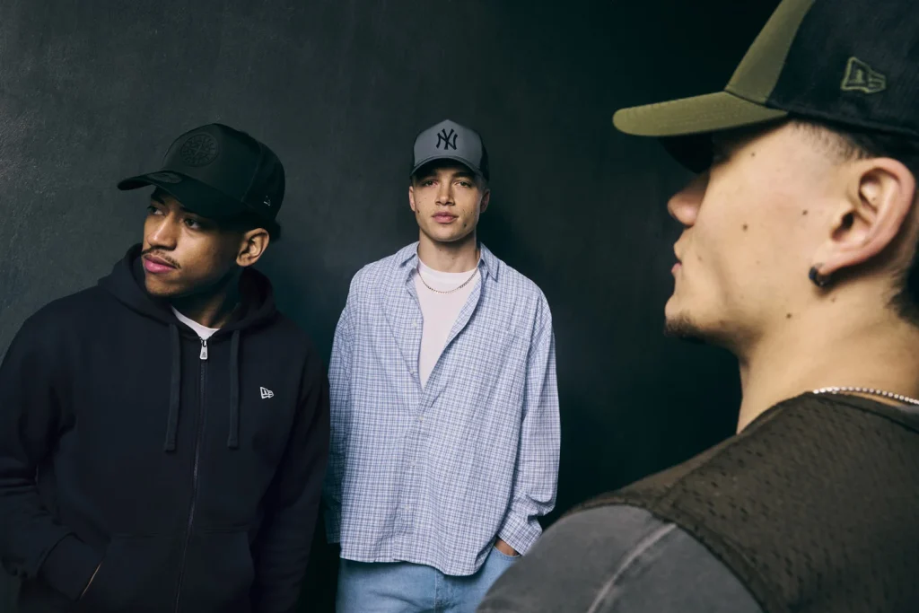 Três jovens com bonés New Era em estilo urbano.
