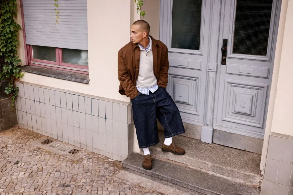 Homem moderno apoiado em porta antiga.