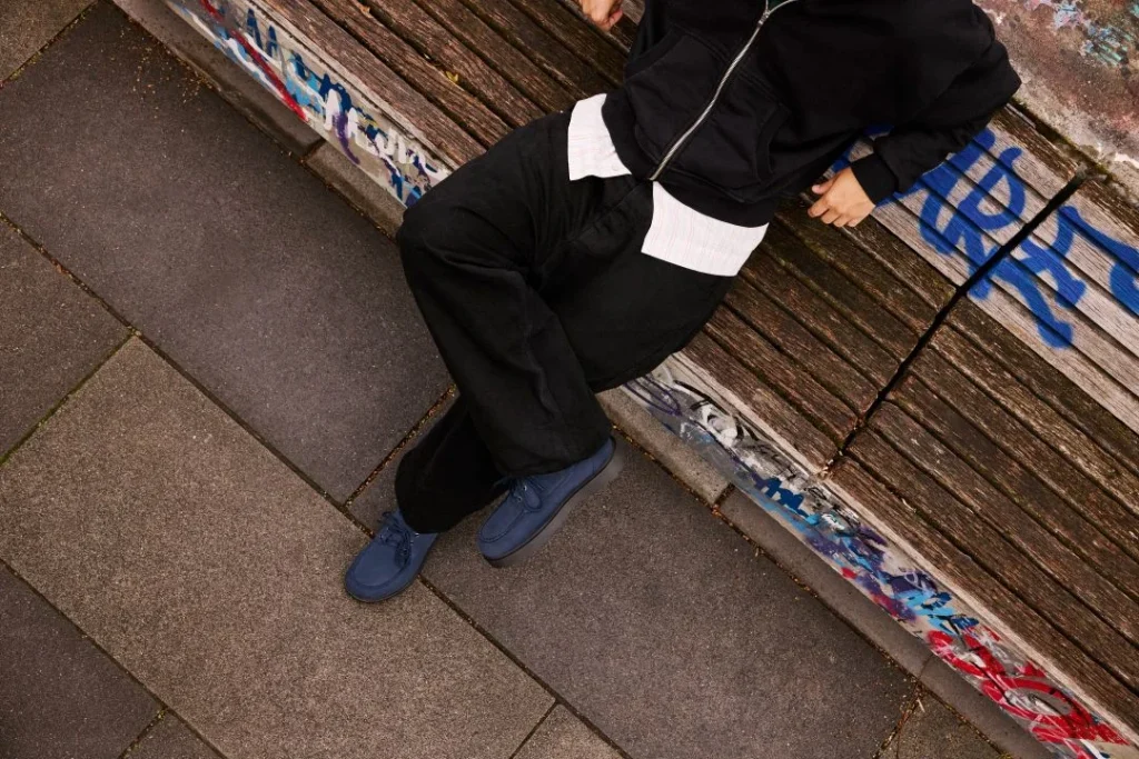 Homem relaxado num banco de madeira com graffiti.