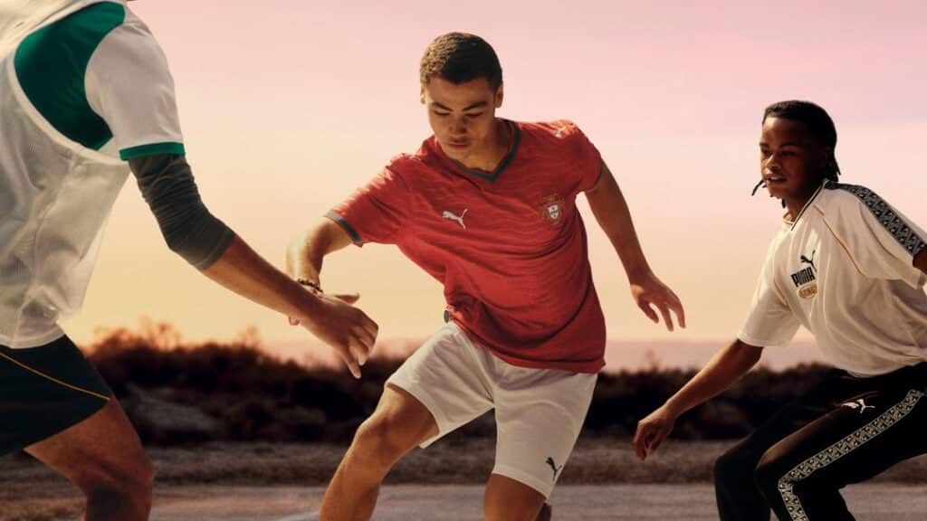 Jovens jogam futebol ao ar livre ao pôr do sol.