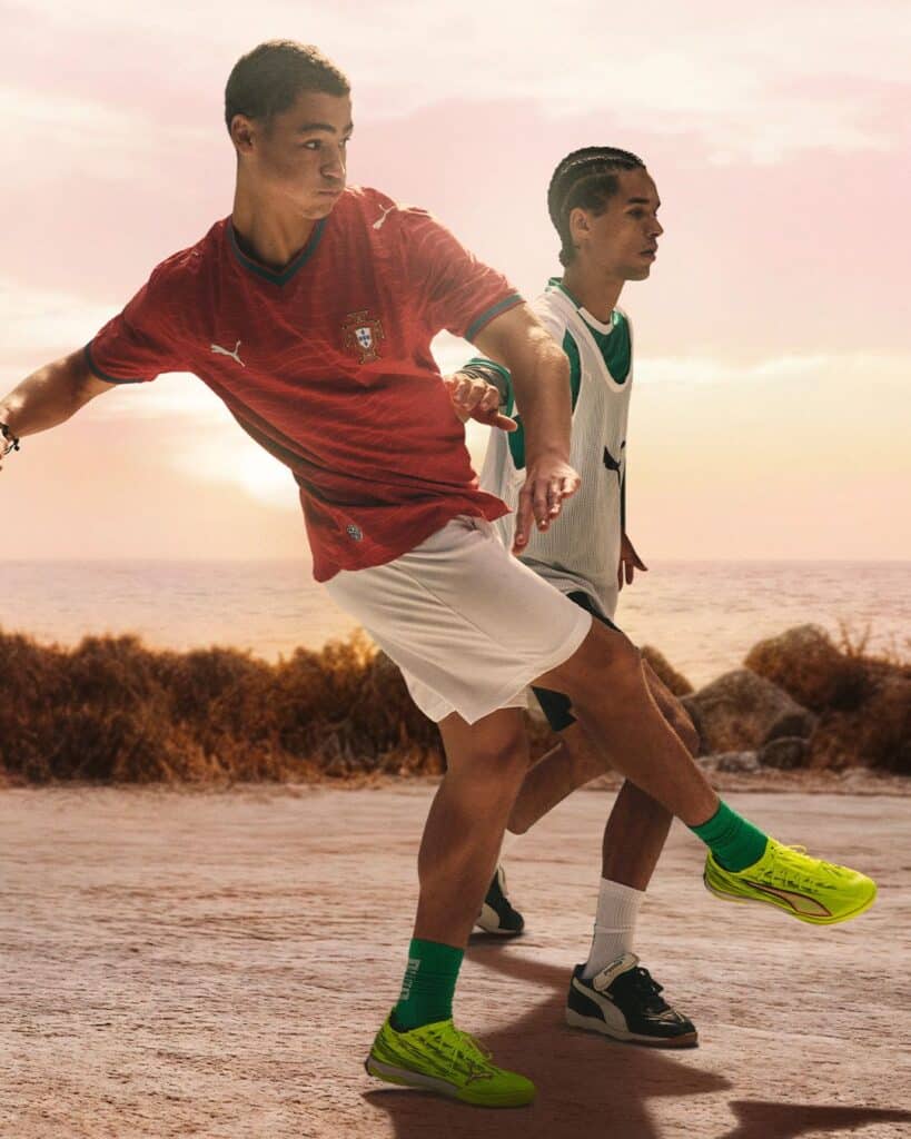 Dois jovens a jogar futebol ao pôr do sol.