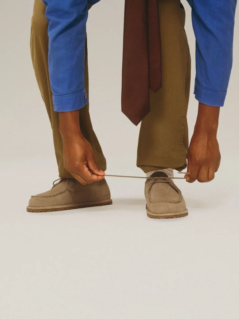 Homem a apertar atacadores de sapatos castanhos.