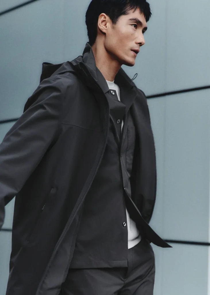 Homem com casaco impermeável cinzento.