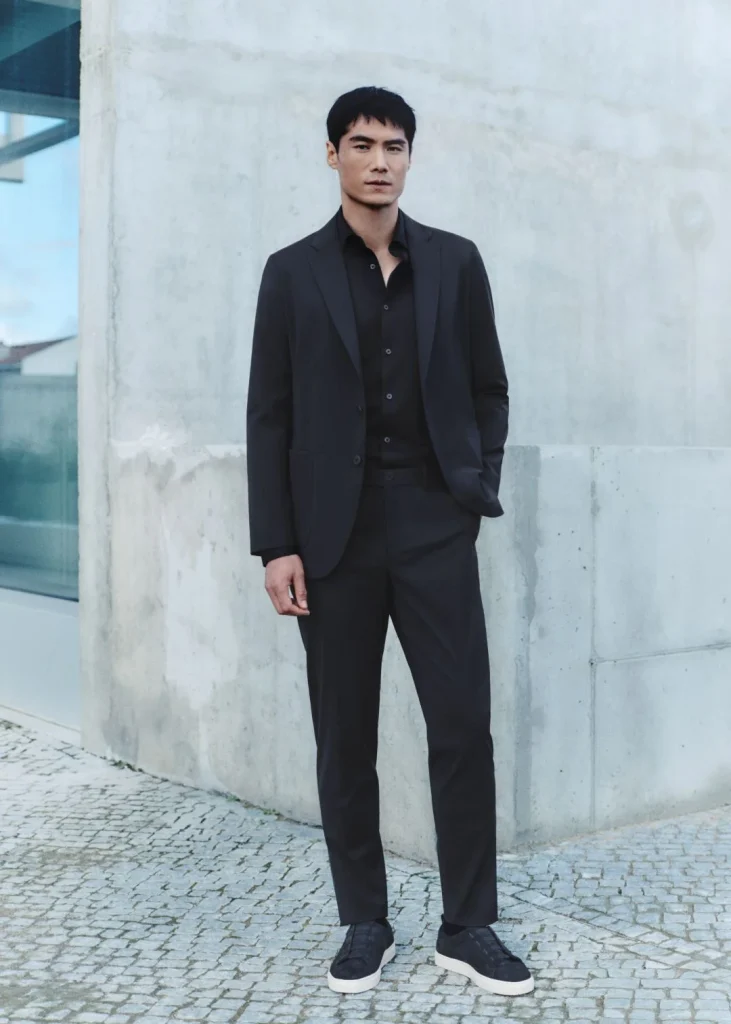 Homem de fato preto e sapatilhas.