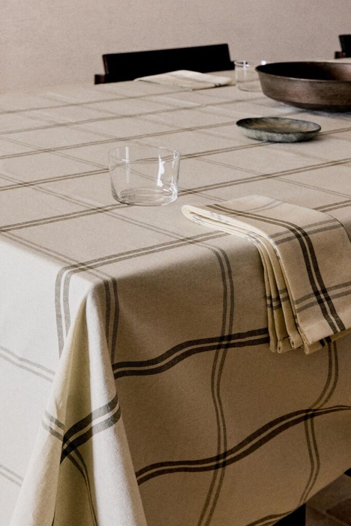 Mesa com toalha xadrez, copo e prato.
