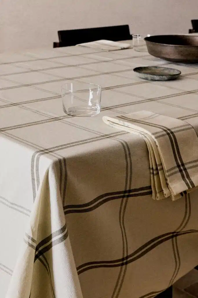 Mesa com toalha xadrez, copo e prato.