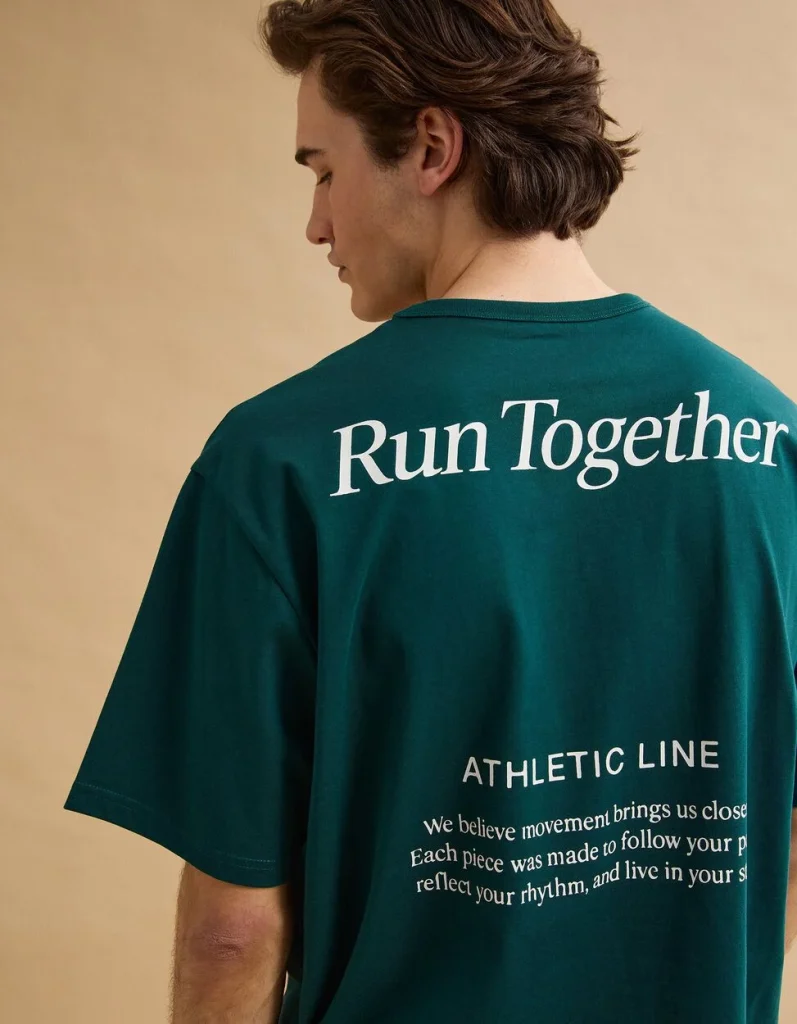 Homem com t-shirt verde-escura "Run Together" da linha atlética.