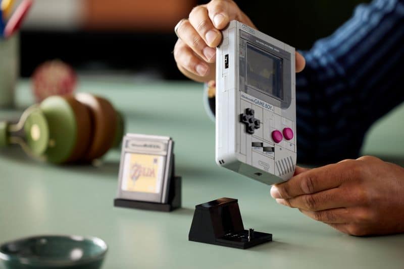 Pessoa segurando console portátil clássico cinza.