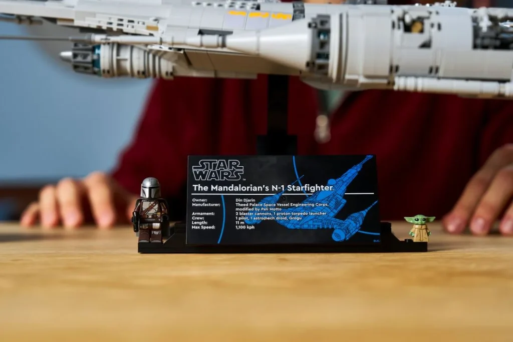 Modelo LEGO do caça estelar N-1 Mandalorian, figuras e placa informativa.