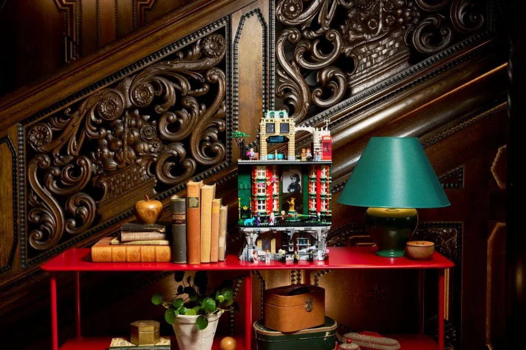 Conjunto LEGO detalhado numa mesa vermelha frente a escada entalhada.