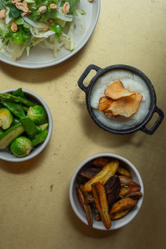 Pratos vegetarianos variados em uma mesa dourada.