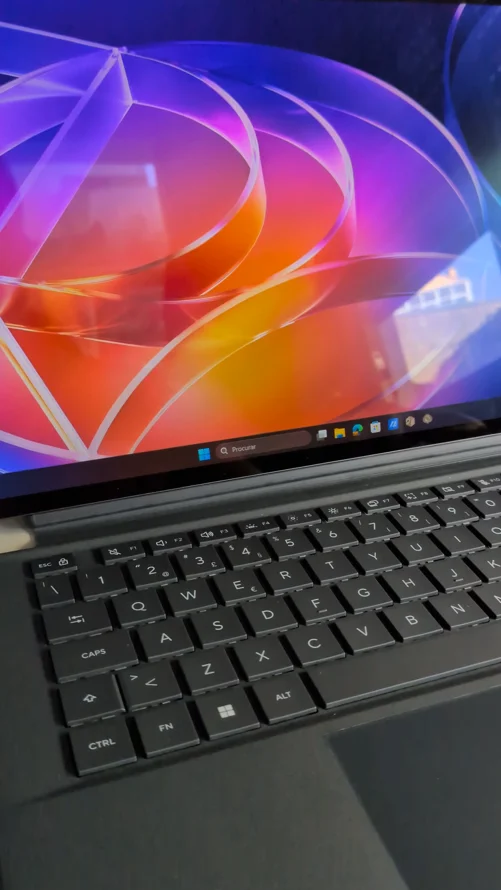Ecrã tátil do Asus ProArt PZ14 a exibir o Windows 11 com fundo colorido abstrato e teclado preto acoplado.