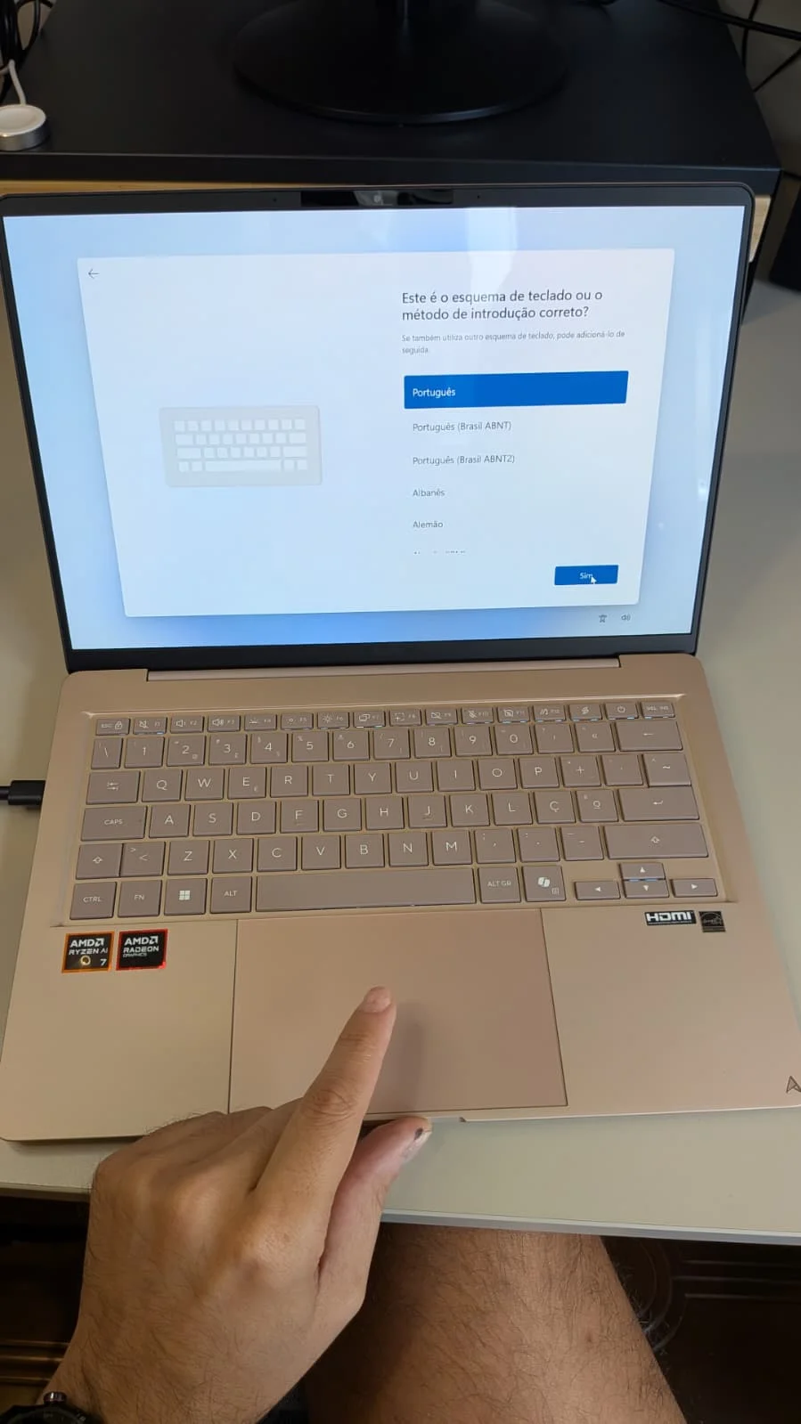 Portátil ASUS Zenbook 14 UX3480KA aberto sobre uma secretária a exibir o ecrã de configuração do Windows com uma mão pousada no touchpad.