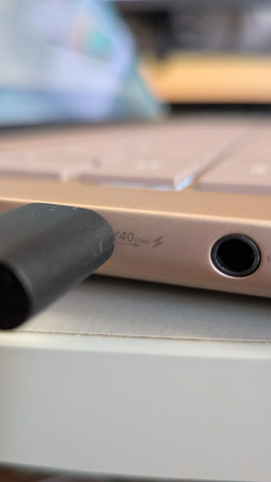 Detalhe lateral do portátil ASUS Zenbook 14 UX3480KA mostrando uma porta USB-C com cabo ligado e indicação de 40 Gbps ao lado de uma entrada de áudio.