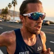 Atleta a correr numa estrada costeira ao pôr do sol.