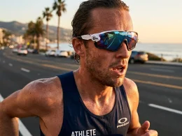 Atleta a correr numa estrada costeira ao pôr do sol.