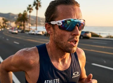 Atleta a correr numa estrada costeira ao pôr do sol.
