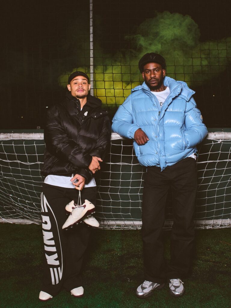 Dois homens de casacos acolchoados frente à rede.