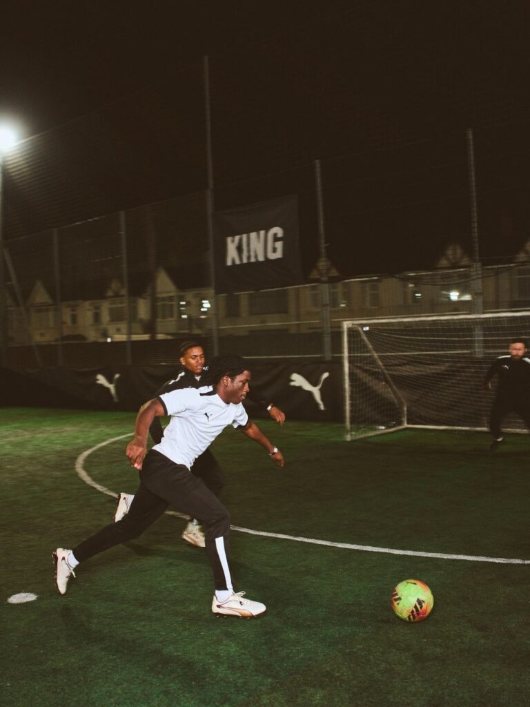 Jogo de futebol noturno com jogadores em ação.