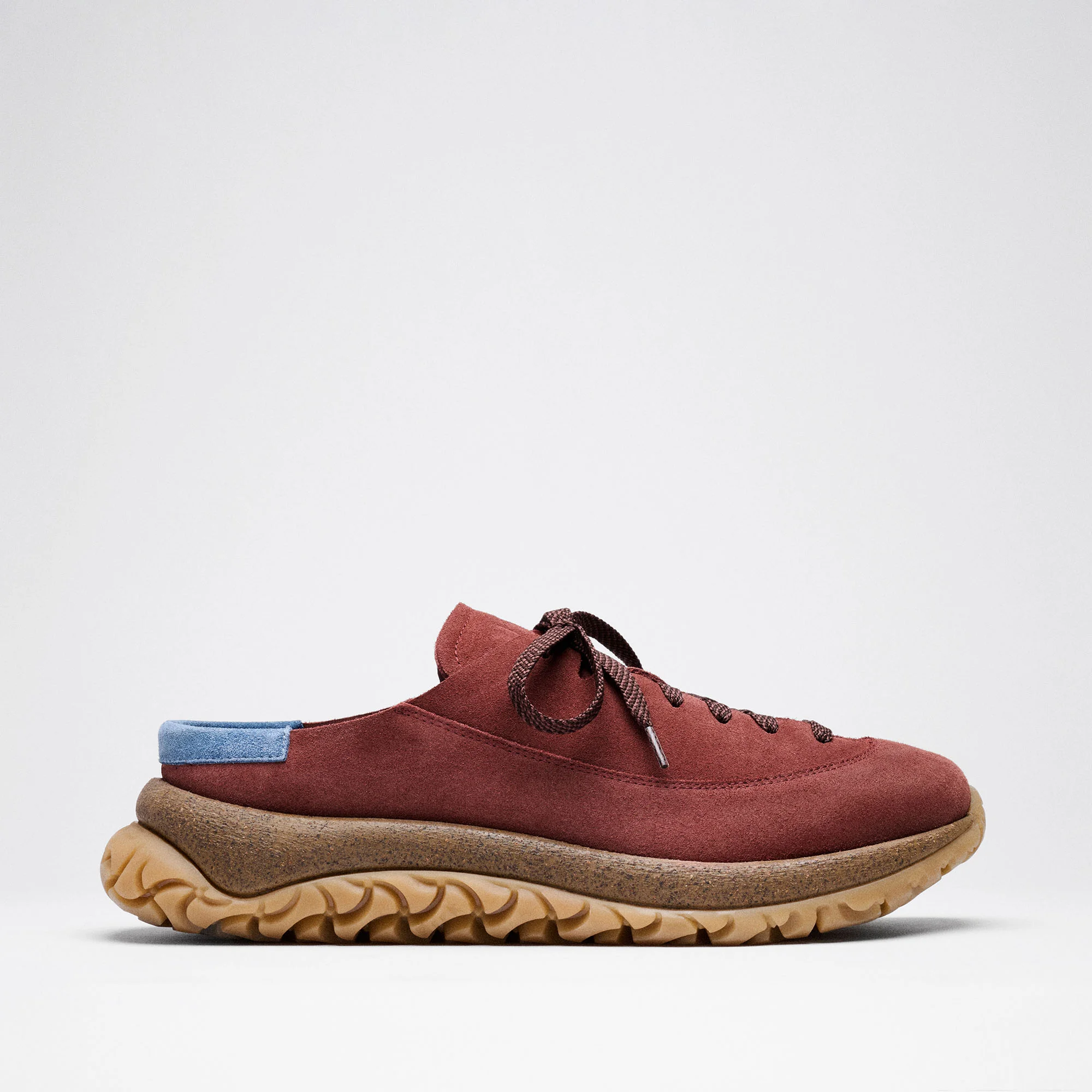 Perfil lateral do calçado híbrido Birkenstock 1774 Uerzell em camurça cor de vinho, com atacadores, detalhe azul no calcanhar, entressola de cortiça e sola de borracha texturizada.
