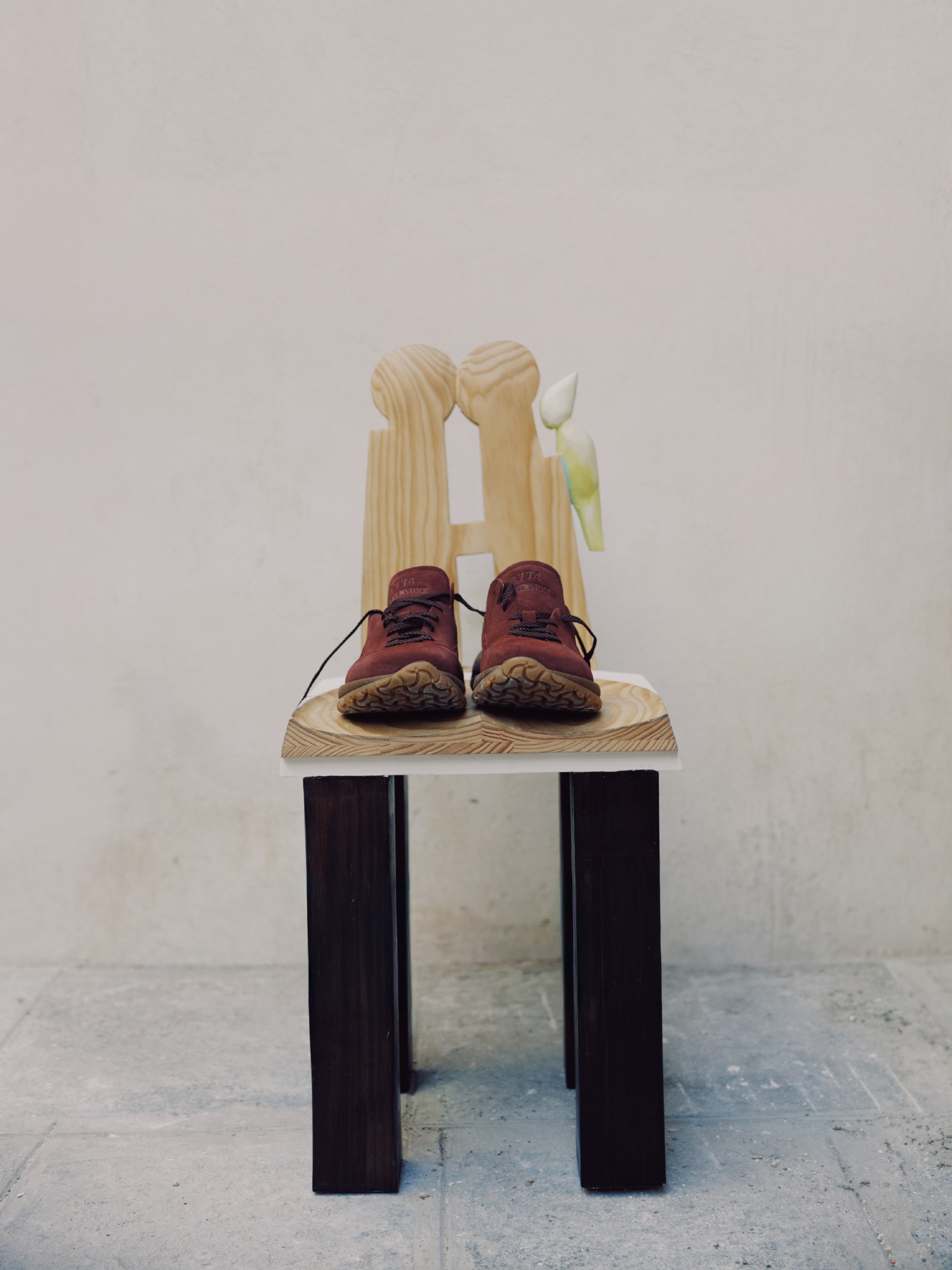 Par de sapatos Birkenstock 1774 Uerzell em camurça cor wine com atacadores sobre uma pequena cadeira de madeira