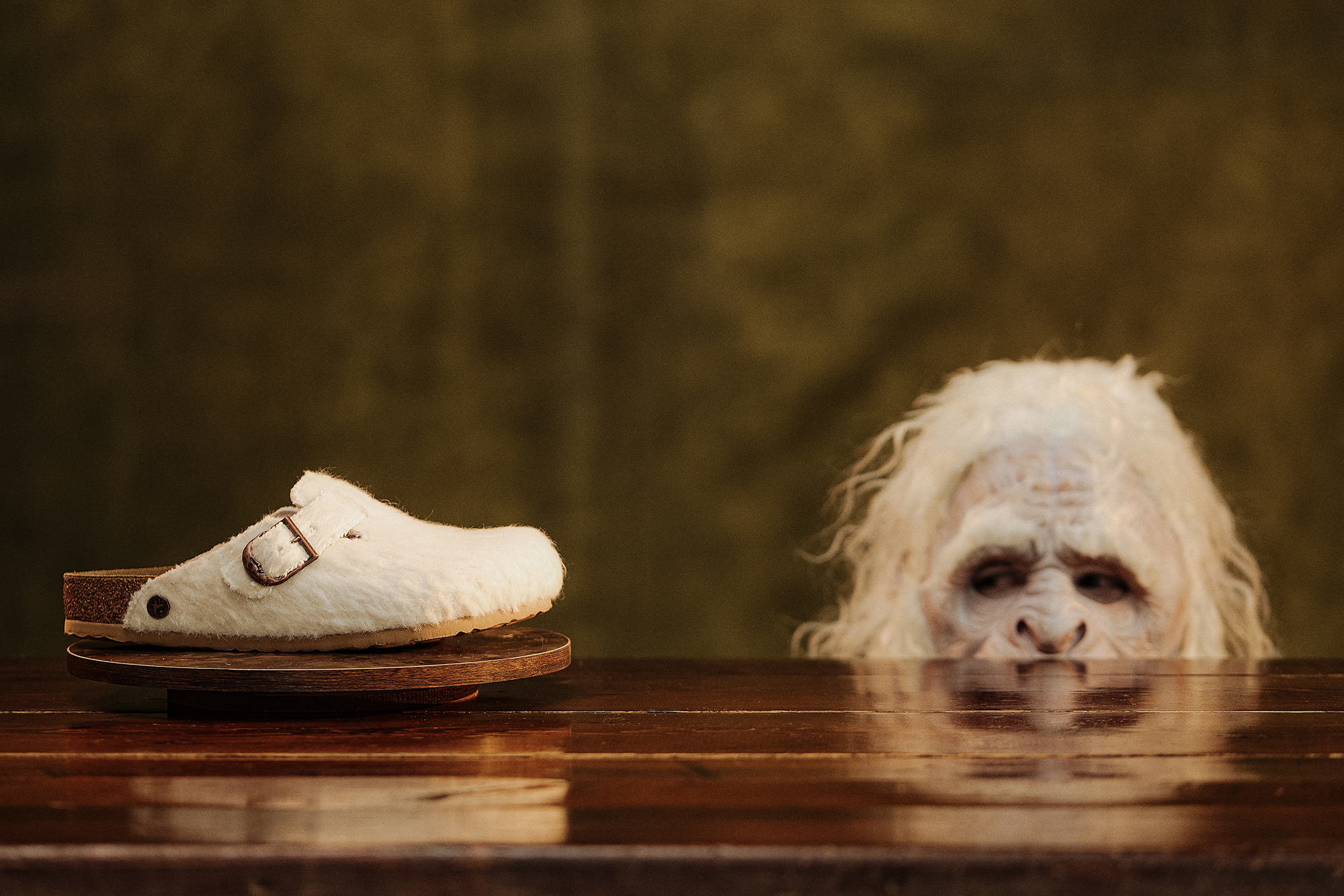 Soco Birkenstock Boston Cole Bennett em feltro de lã off-white sobre base de madeira com figura de yeti a espreitar ao fundo