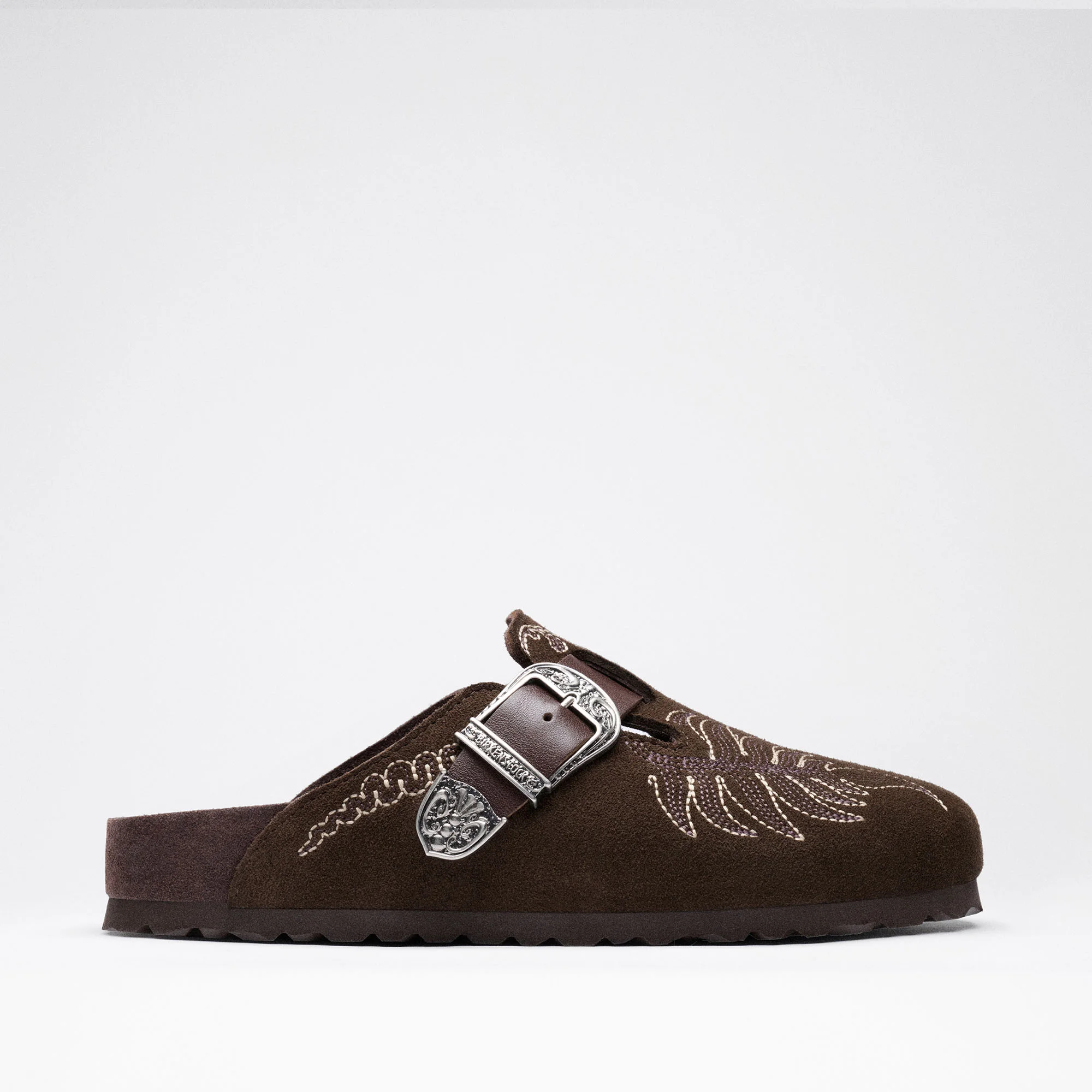 Tamanco lateral Birkenstock by ETRO Boston em camurça castanha escura com bordados claros e fivela prateada detalhada