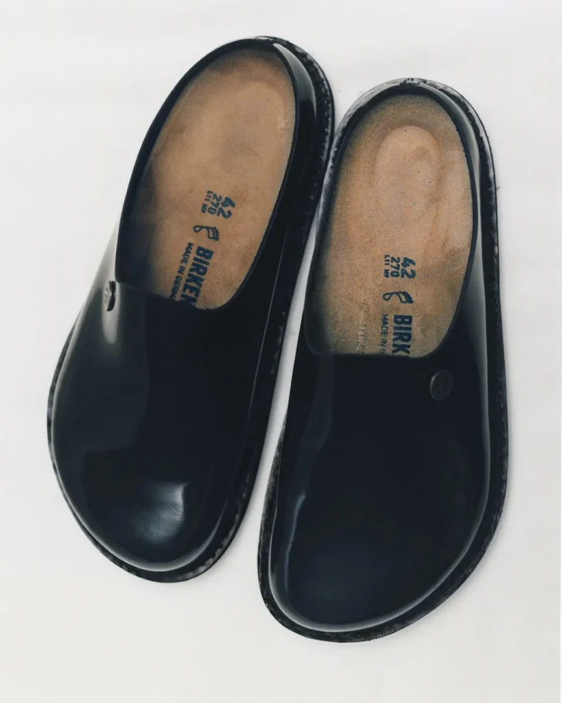 Par de tamancos Birkenstock pretos e brilhantes.