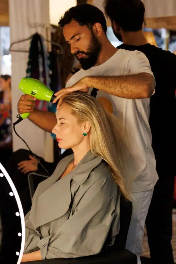 Cabeleireiro seca cabelo loiro em salão.