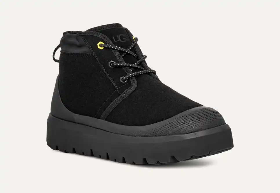 Bota preta UGG com sola grossa de borracha e detalhes amarelos nos atacadores, destacada entre as melhores botas de inverno para homem.