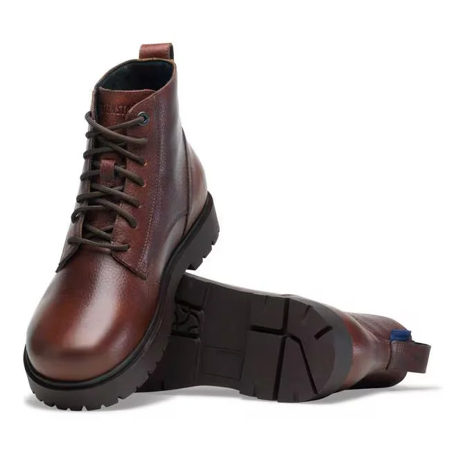 Par de botas de inverno para homem em pele castanha com atacadores, exibindo uma bota vertical e outra deitada que revela a sola robusta.