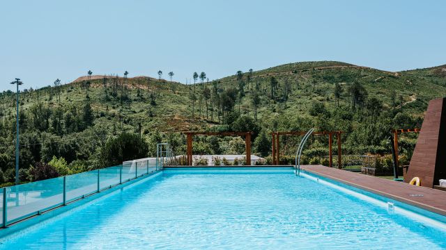 Piscina exterior com vista para montanhas verdes.