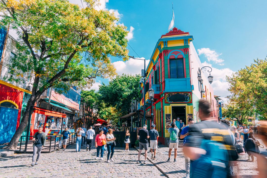 Rua empedrada com edifícios coloridos em azul, vermelho e amarelo no Caminito em Buenos Aires, ponto de partida do cruzeiro na América do Sul.