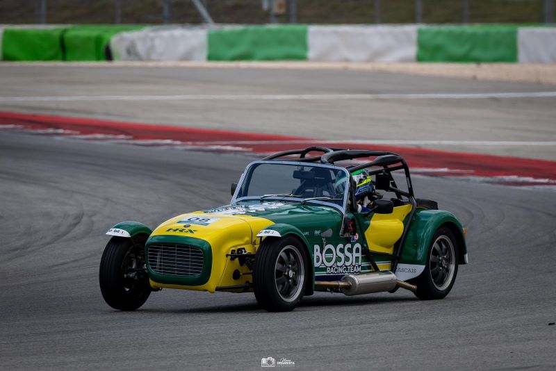 Carro de corrida verde e amarelo na pista.