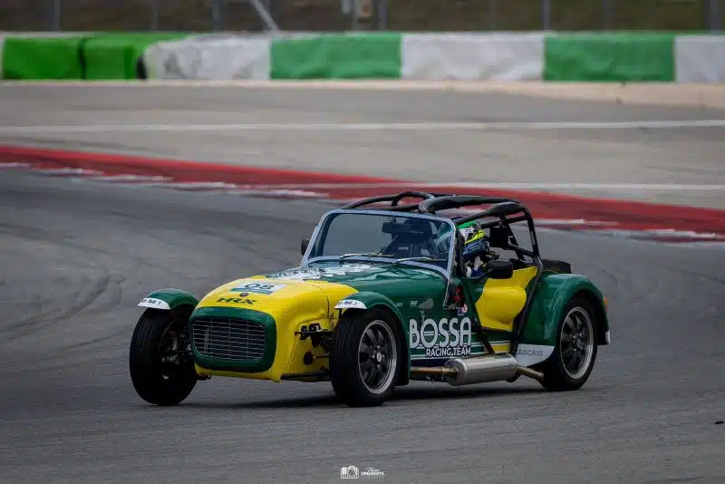 Carro de corrida verde e amarelo na pista.