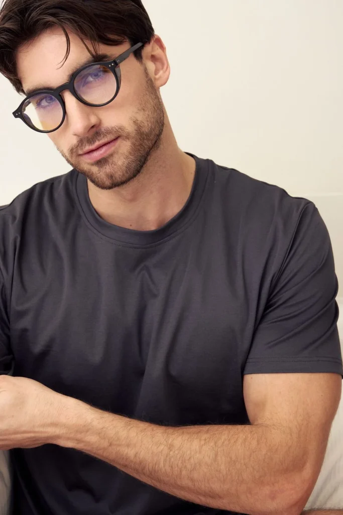 Retrato de homem, óculos redondos, t-shirt cinza-escuro.