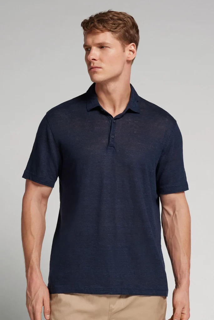 Homem a usar polo azul escuro e calças beges.