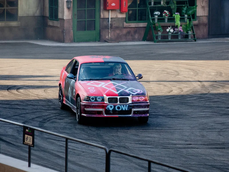 Carro BMW decorado com graffiti a circular numa pista.