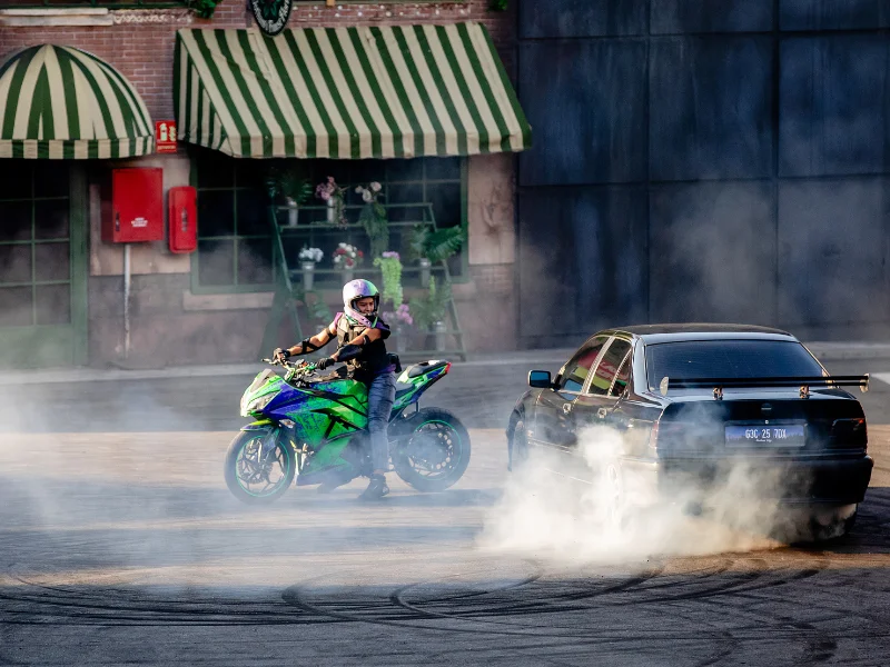 Mota e carro a realizar acrobacias com fumo denso.